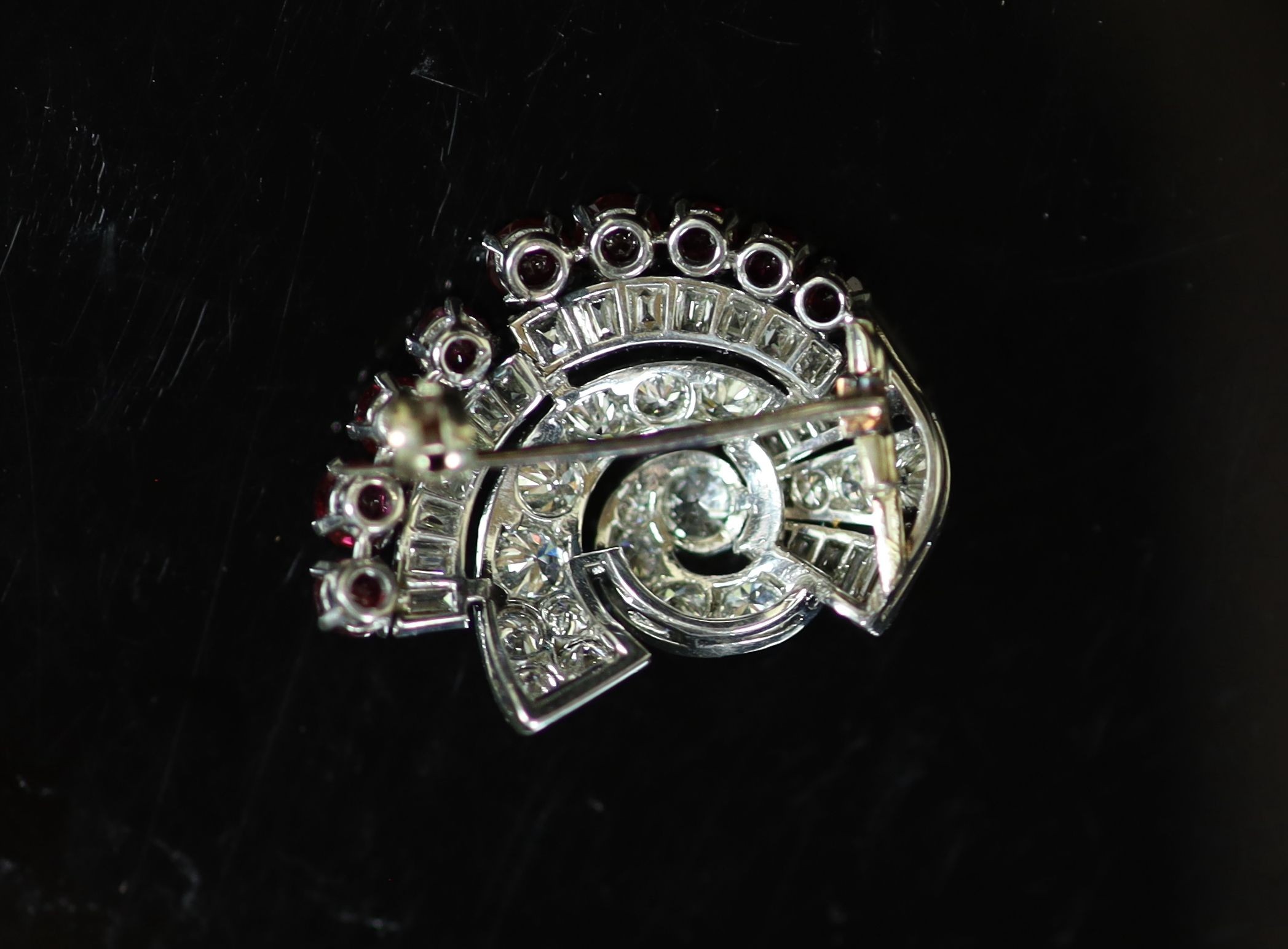 A mid 20th century white gold, ruby and diamond set fan shaped scroll brooch